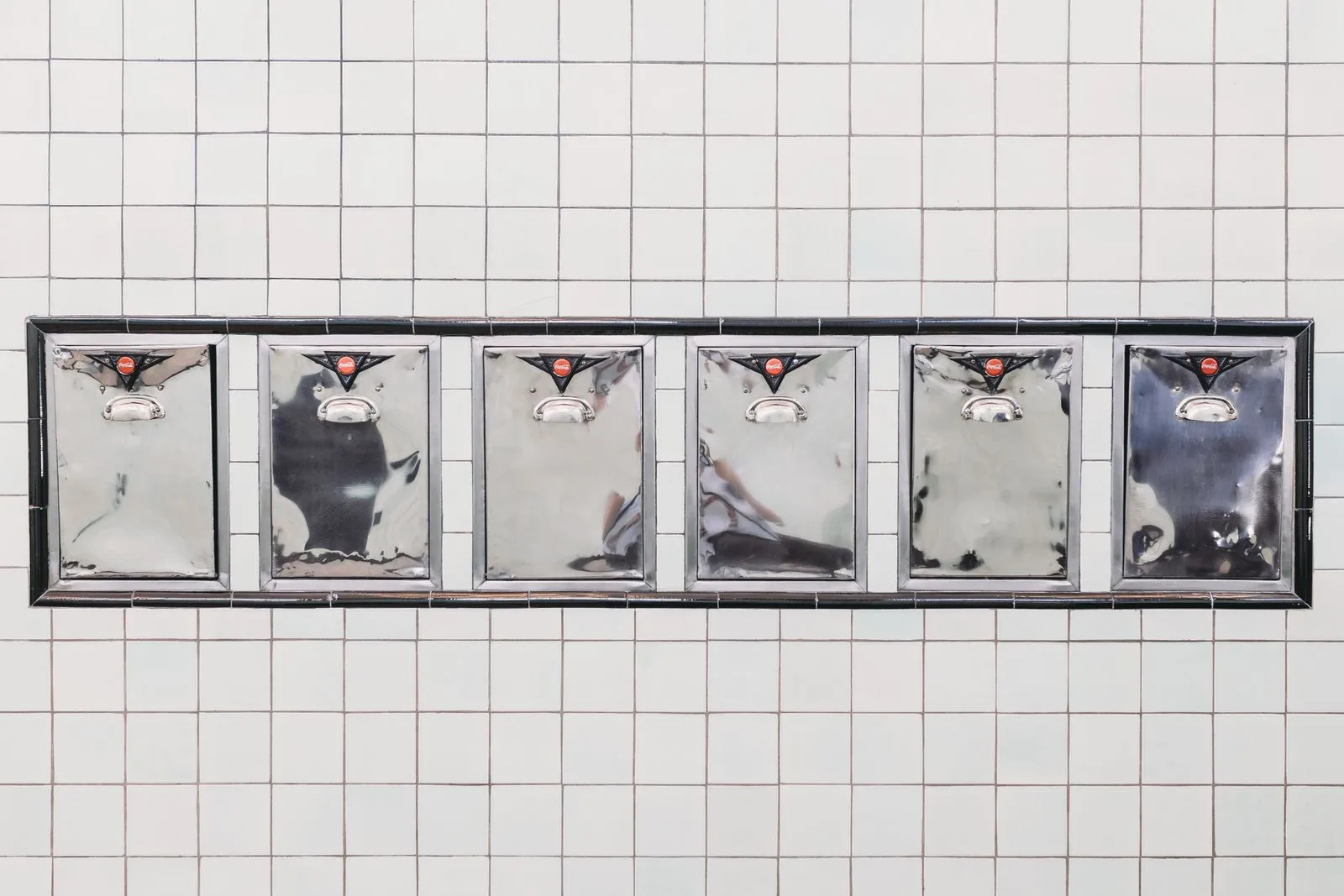 Six silver mailboxes mounted on a tiled wall, Indianapolis, IN.
